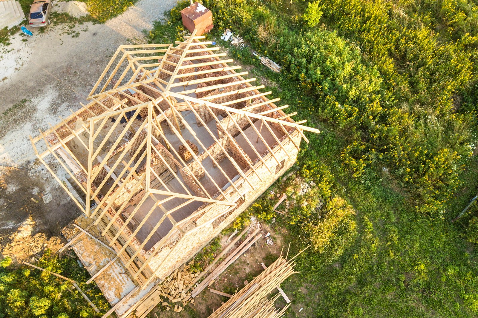 Aerial view of unfinished brick house with wooden roof structure under construction